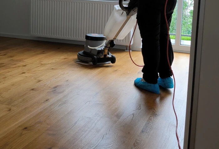 Ein Mitarbeiter reinigt einen Parkettboden mit einer professionellen Maschine